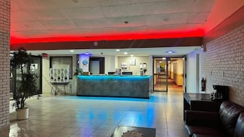 A hotel lobby with a reception desk, seating area, and a potted plant.