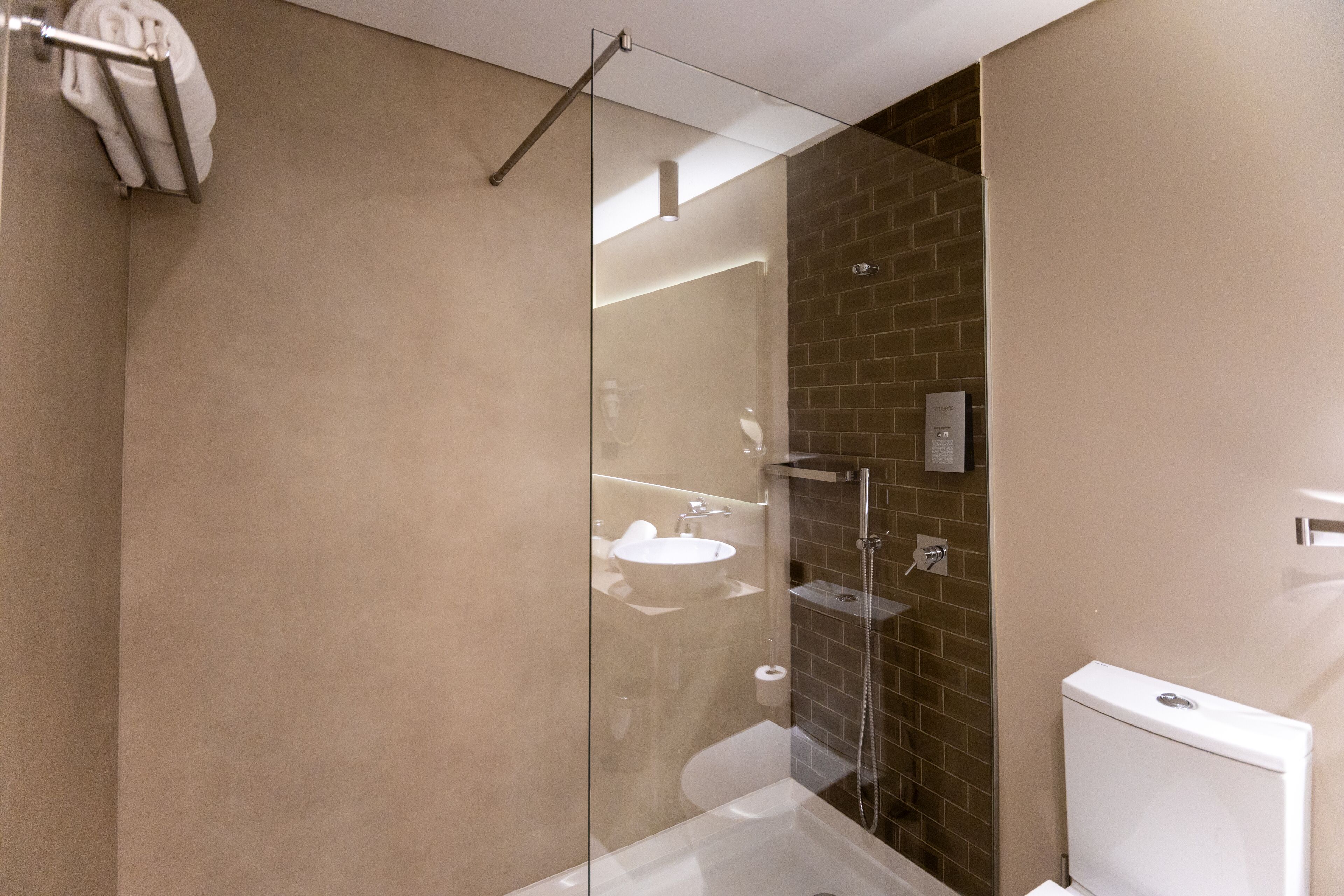 A modern bathroom with a glass-enclosed shower, a white sink, and a visible toilet.