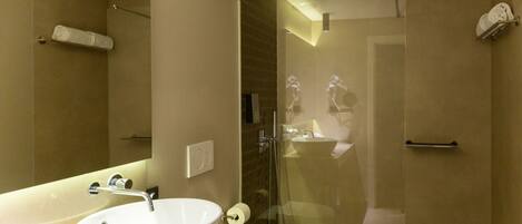 A modern bathroom with a large sink, toilet, and glass-enclosed shower.