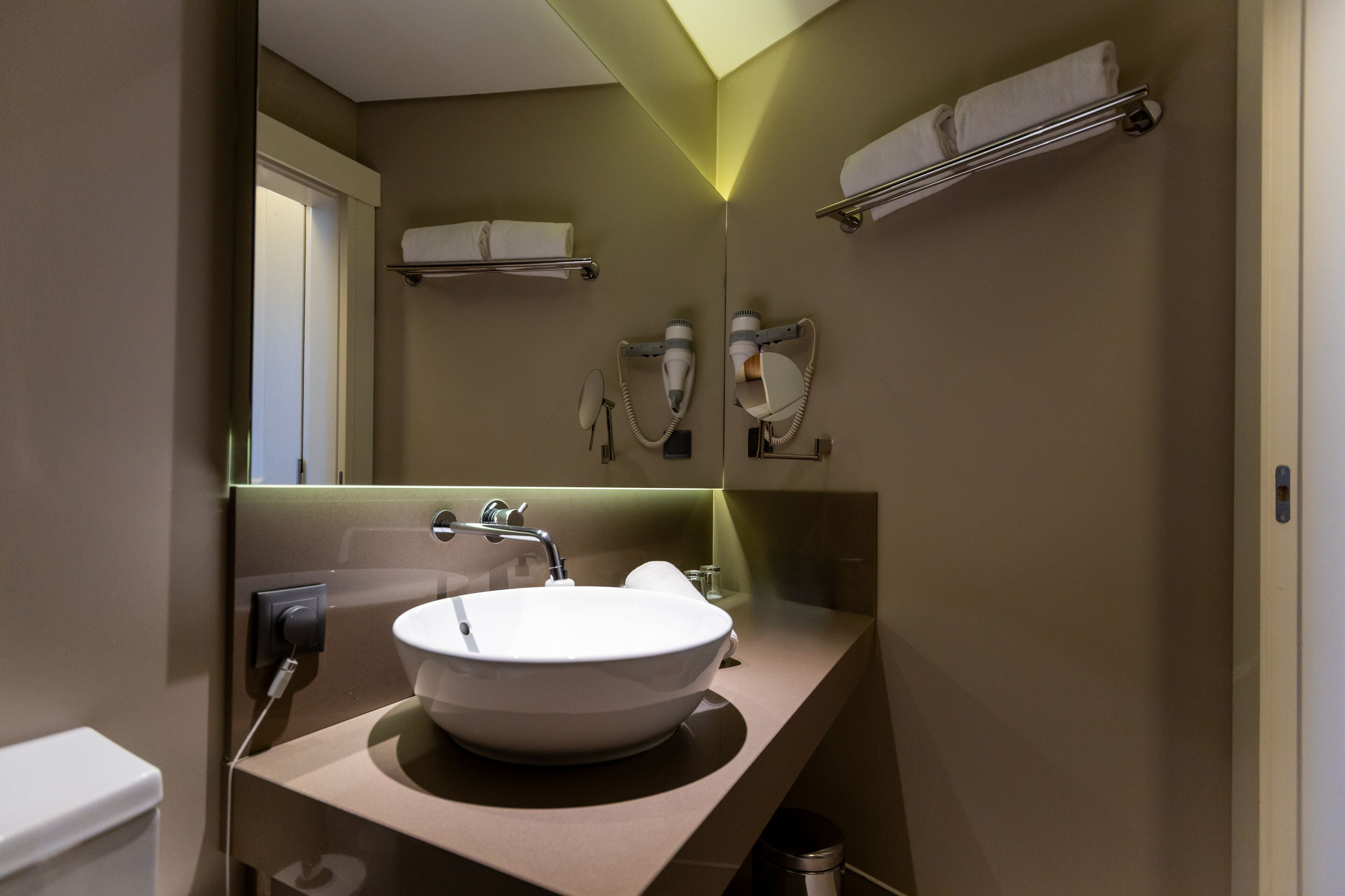 A modern bathroom with a white sink, a mirror, and a towel rack.
