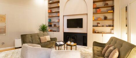 A living room with a fireplace, sofas, a coffee table, and bookshelves.