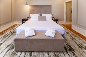 Una cama bien hecha con sábanas blancas, cabecera y dos mesitas de noche con lámparas.