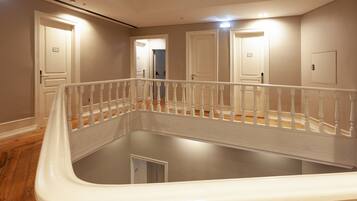 A spacious, well-lit room with a large, empty pool, wooden flooring, and a white railing.