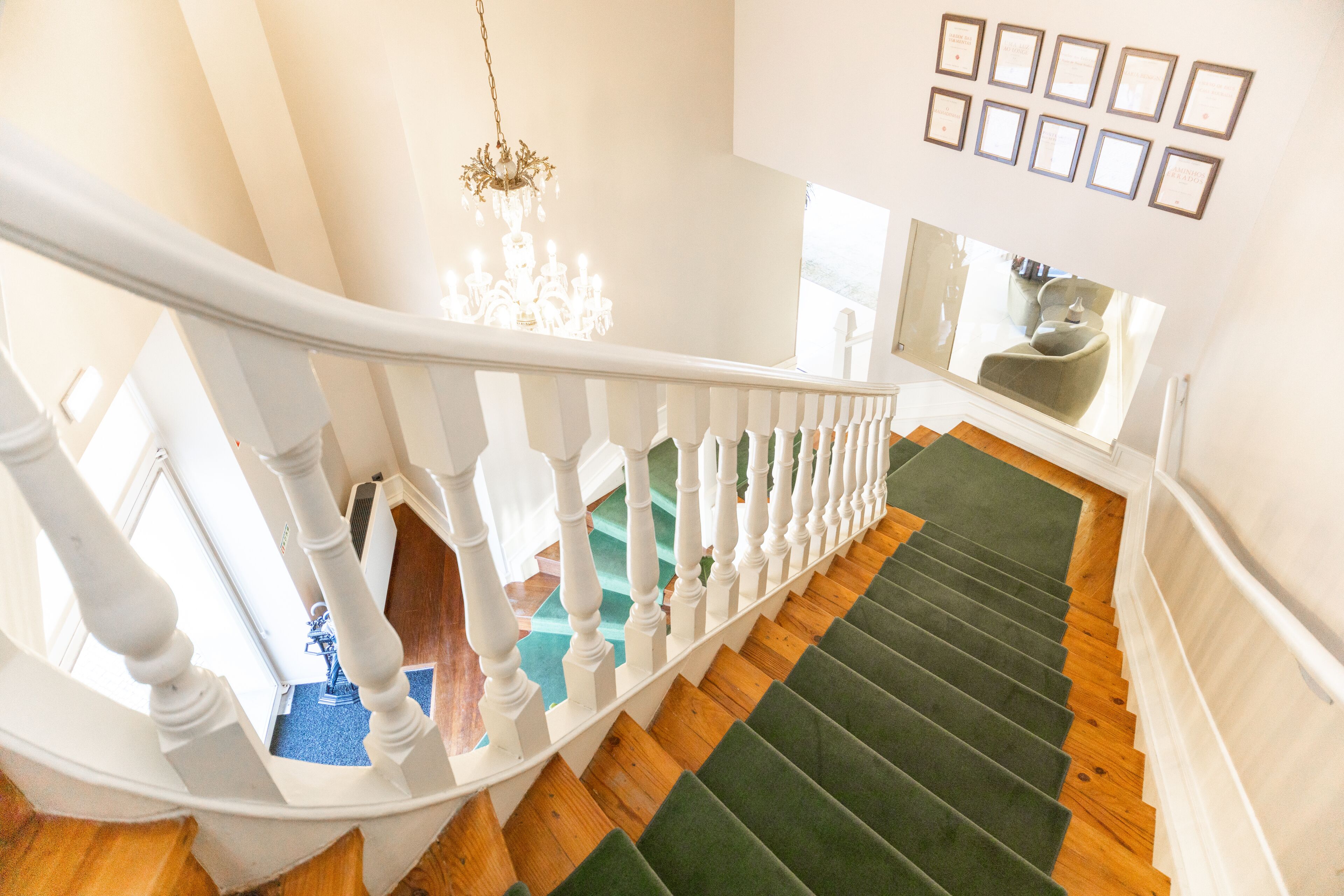 A staircase with white balusters, green carpeted steps, and wooden flooring.