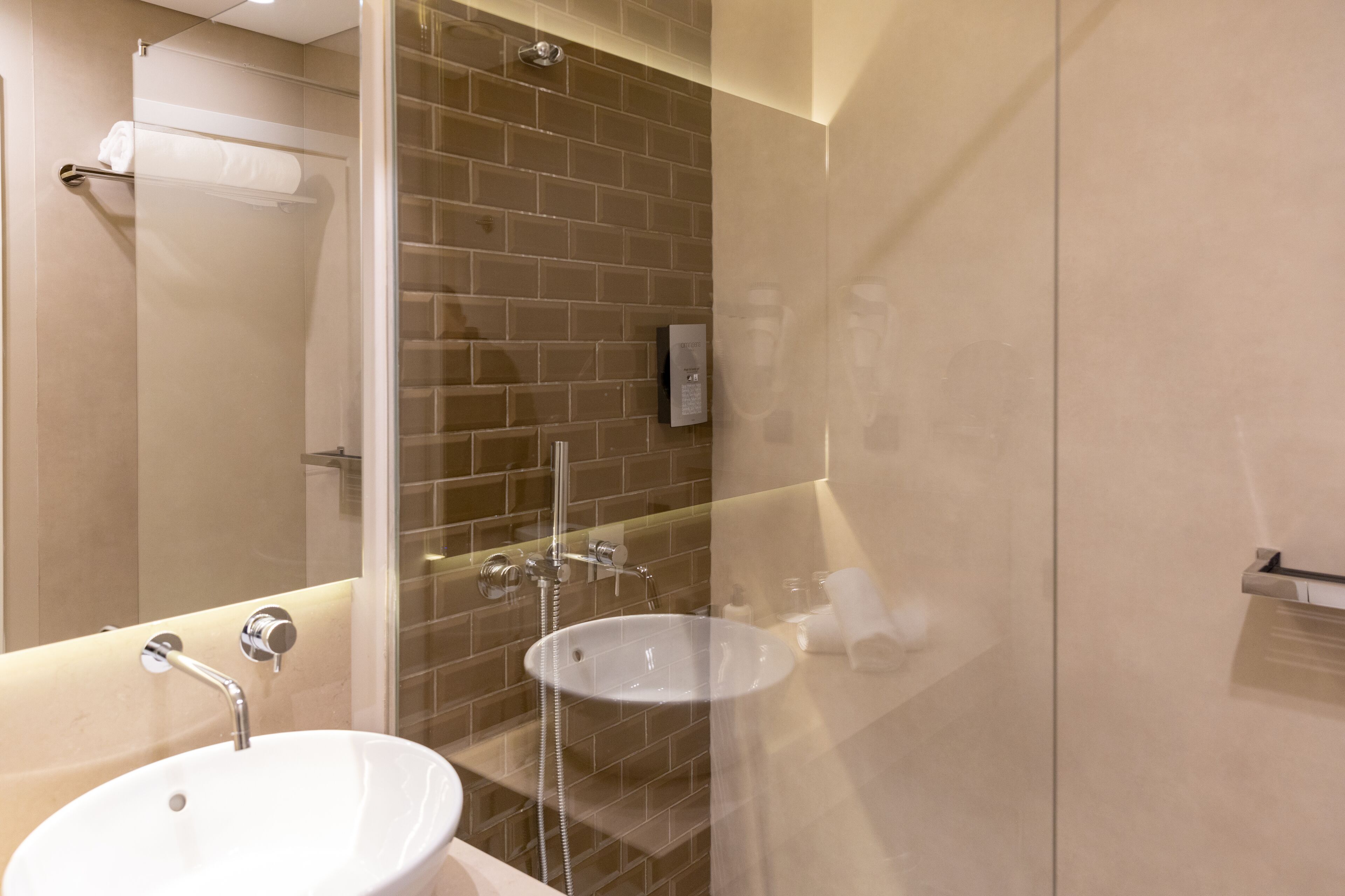 A modern bathroom with a glass-enclosed shower, a white sink, and a towel rack.