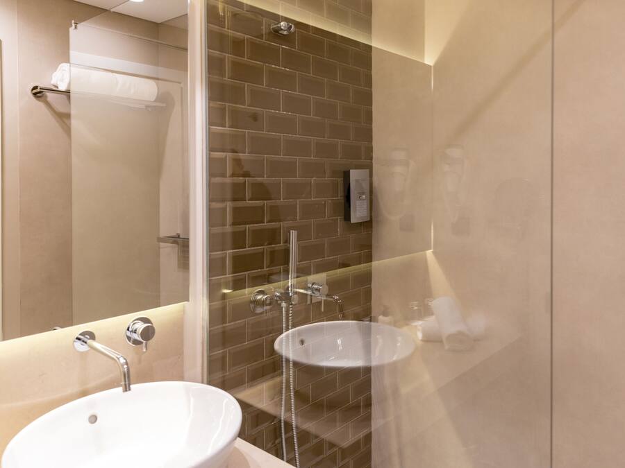 A modern bathroom with a glass-enclosed shower, a white sink, and a towel rack.