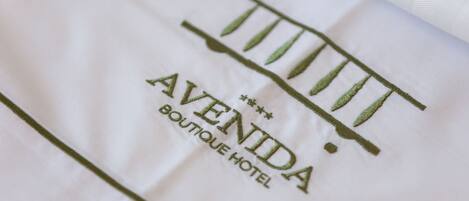 A white fabric with embroidered text reading "AVENIDA BOUTIQUE HOTEL".