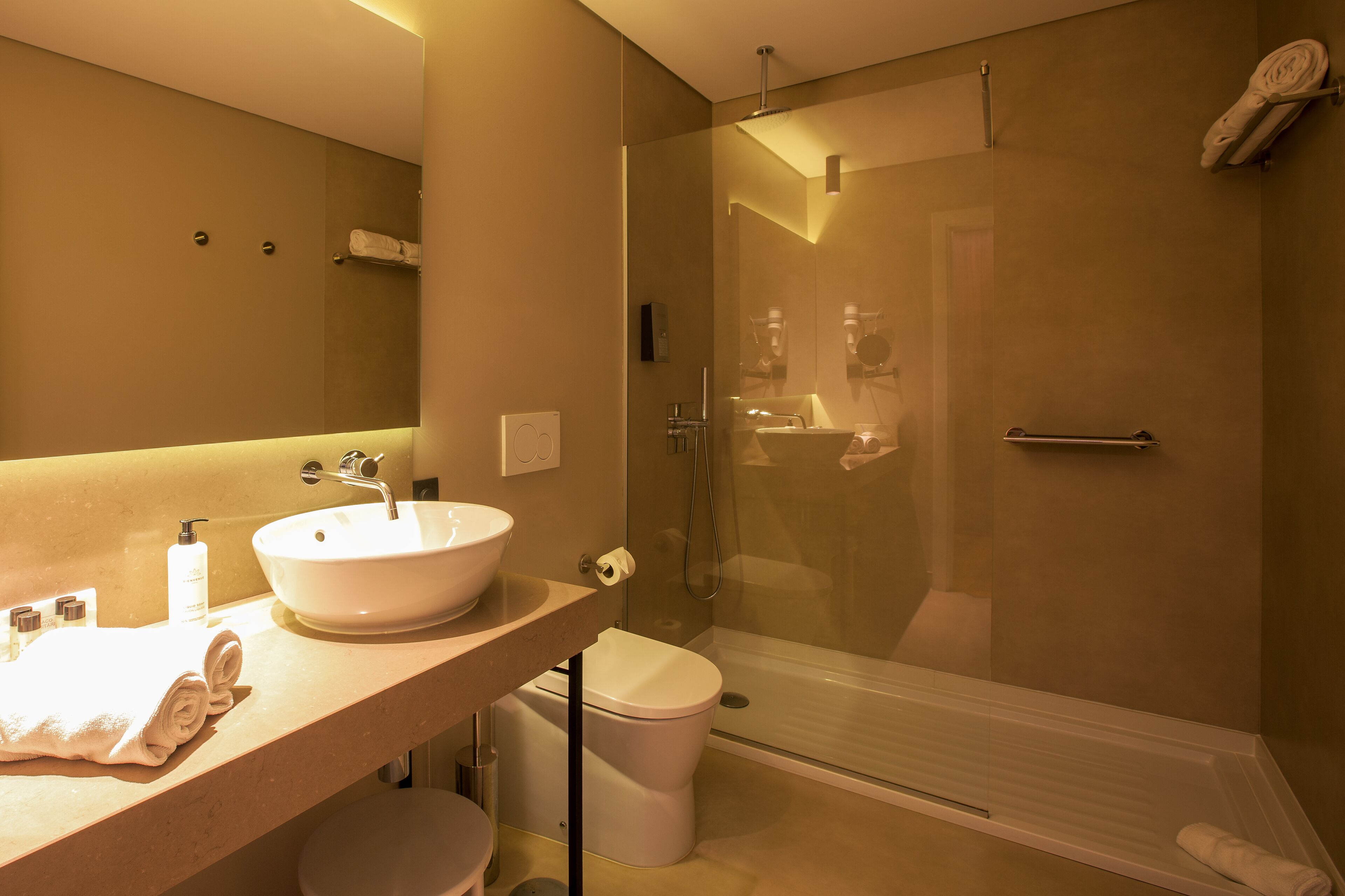 A modern bathroom with a large sink, toilet, and glass-enclosed shower.