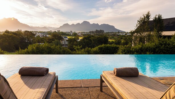 A poolside area with two lounge chairs and a view of mountains in the background.