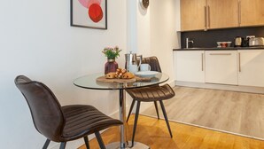 Une cuisine moderne avec des meubles en bois, une table ronde en verre et deux chaises.