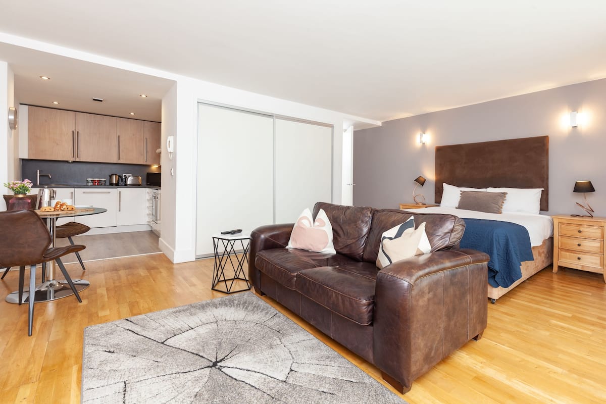 A modern apartment with a living area, a kitchen, and a bedroom.