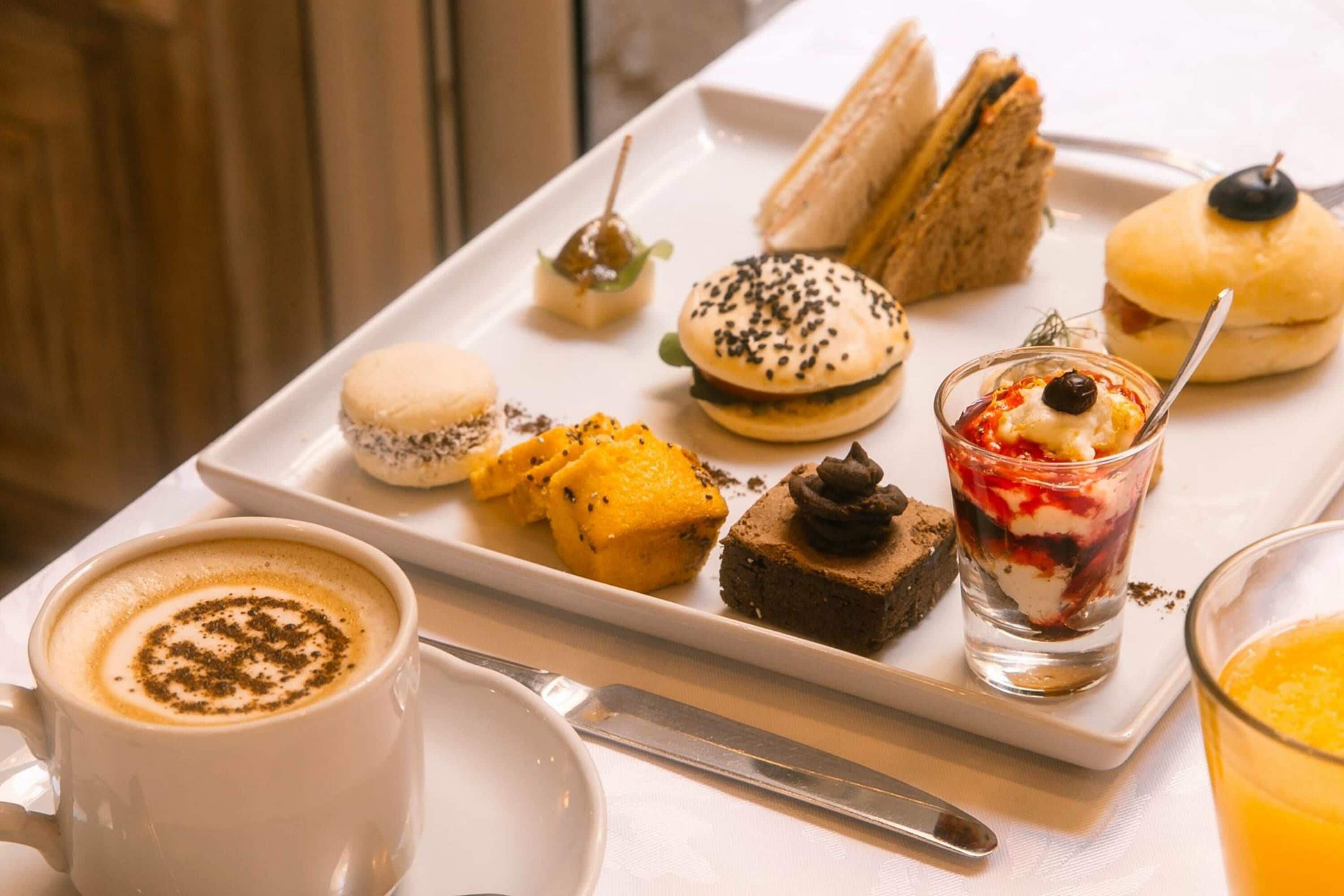 Un plato blanco con diversos postres y una taza de café.