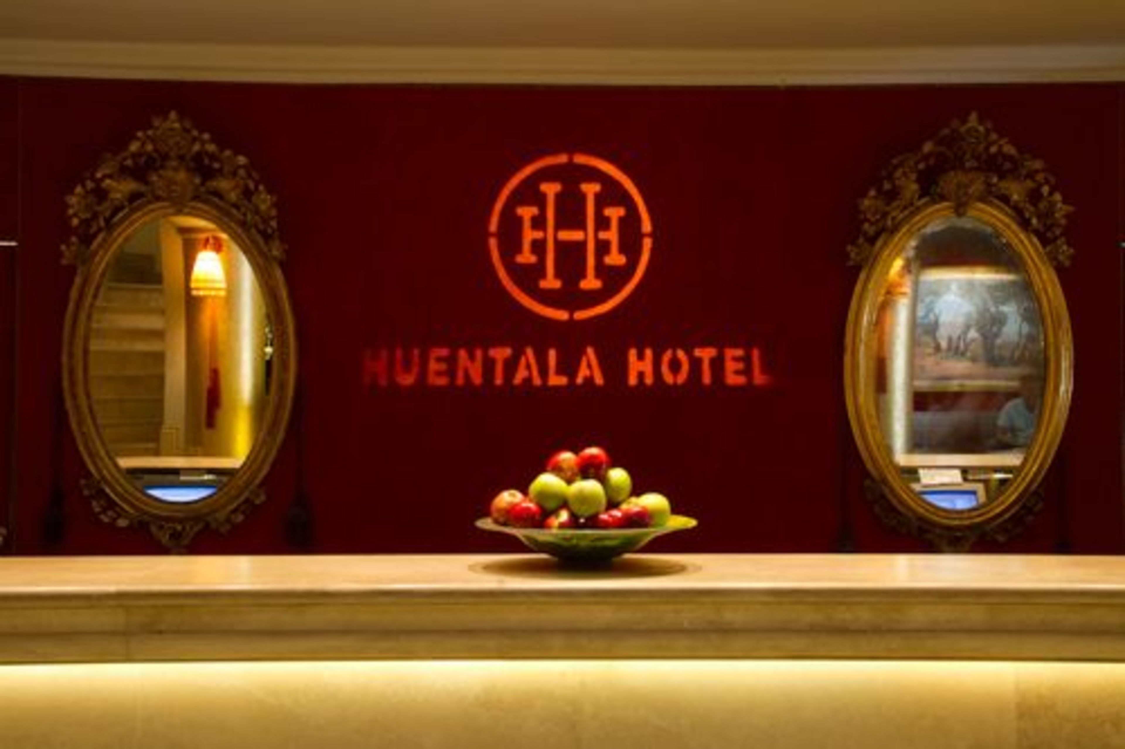 La recepción principal del Hotel Huentalá, con un frutero en la barra y dos espejos ornamentales a cada lado.
