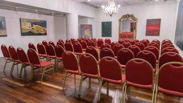 A conference room with rows of red chairs, a chandelier, and artwork on the walls.