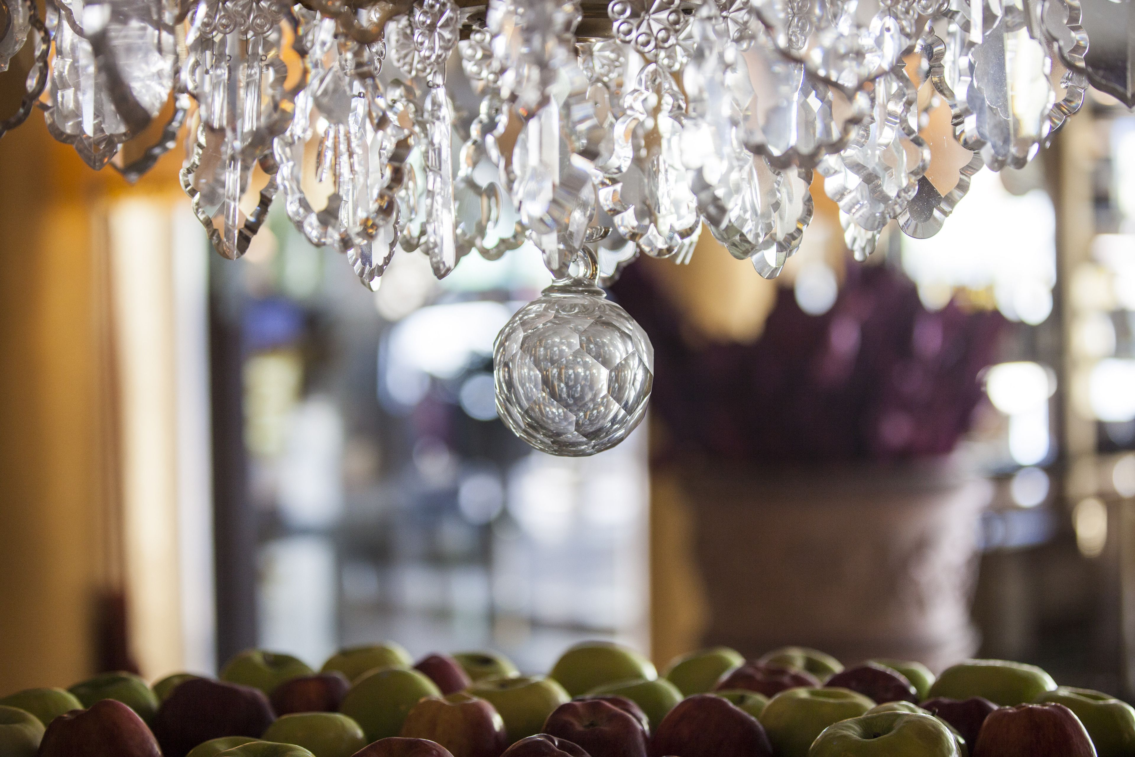 Un candelabro con múltiples elementos de cristal y un único adorno de cristal colgando.