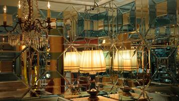A luxurious interior with a chandelier, mirrored walls, and a table with a lamp.