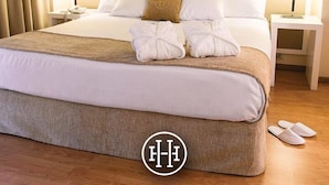 A hotel room with a large bed, two bedside lamps, a headboard, and a framed picture on the wall.