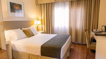 Una habitación de hotel con una cama grande, un escritorio y una silla.