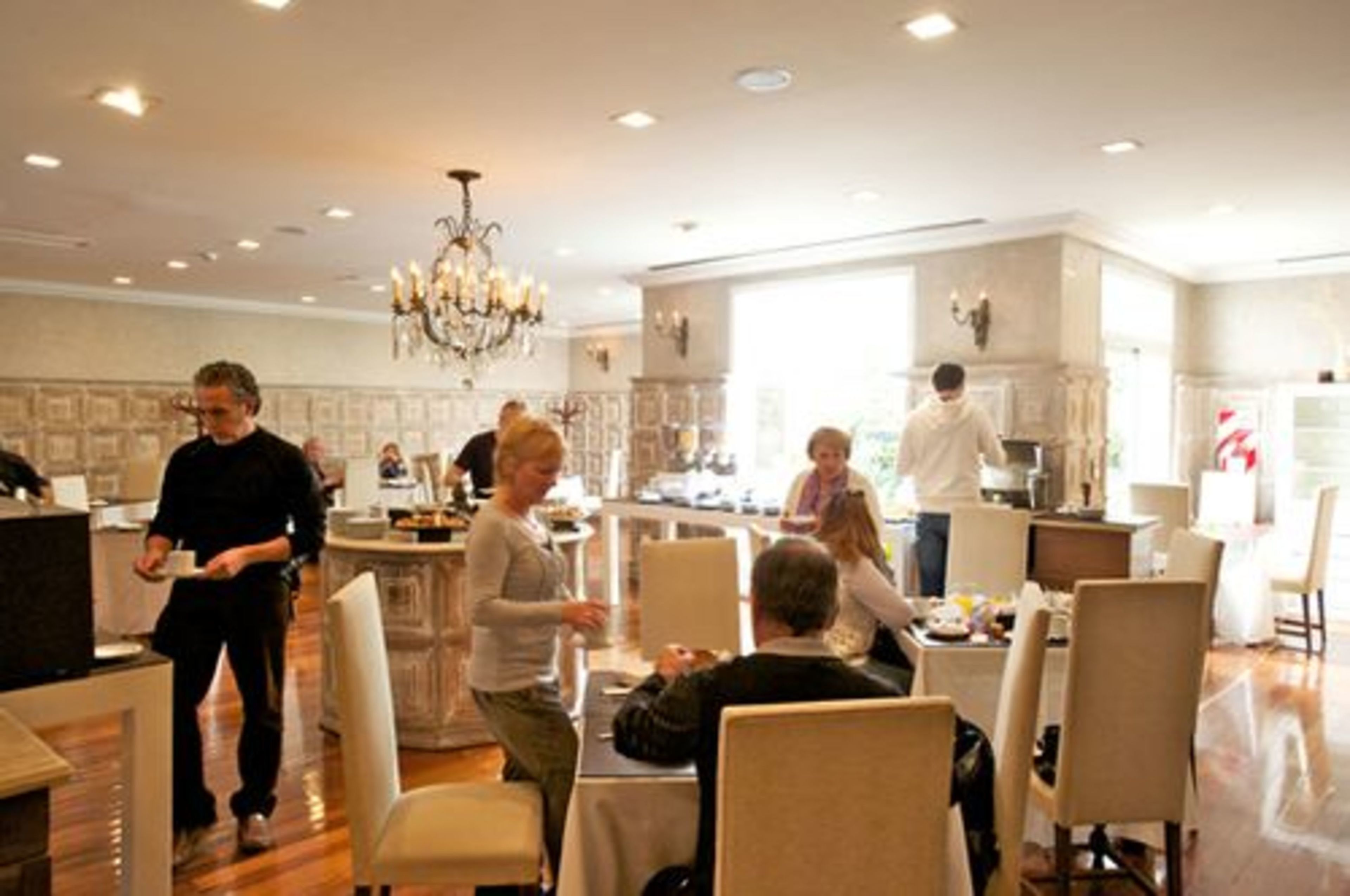 A spacious dining area with high ceilings, chandeliers, and a modern interior design.