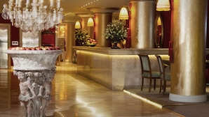A luxurious lobby with a marble reception desk, gold columns, and a crystal chandelier. - Huentala Hotel (Mendoza)