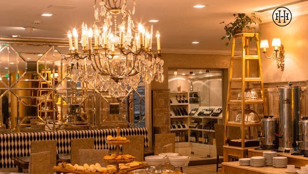 A luxurious hotel lobby with a grand chandelier, seating areas, and a wine and beverage station. - Huentala Hotel (Mendoza)