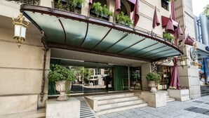 A hotel entrance with a covered entrance, steps leading up to the door, and potted plants. - Huentala Hotel (Mendoza)