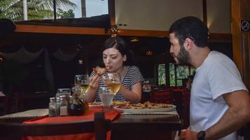 Two people dining at a restaurant with a red tablecloth, wine glasses, and a variety of condiments.