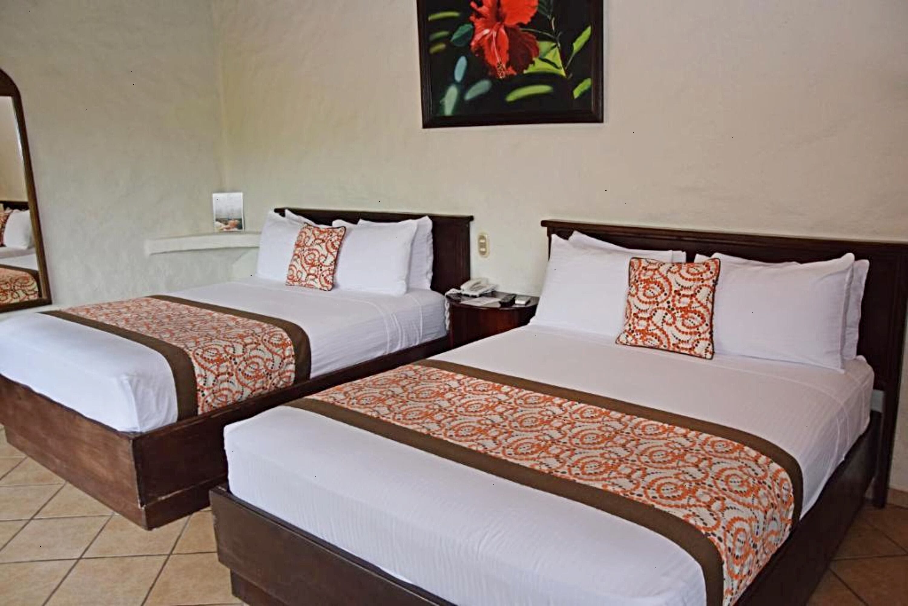 Two single beds with matching headboards and footboards, a bedside table with a lamp, and a framed picture on the wall.