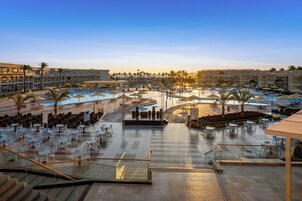 A resort pool area with multiple pools, sun loungers, and outdoor seating.
