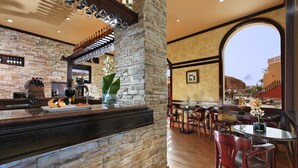 A restaurant with a stone wall, a bar area, and a view of a building through an archway. - Pickalbatros Aqua Blu Sharm El Sheikh (Sharm El Sheikh)