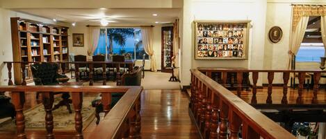 A spacious living room with a wooden staircase, a bookshelf, and a wall of framed pictures.