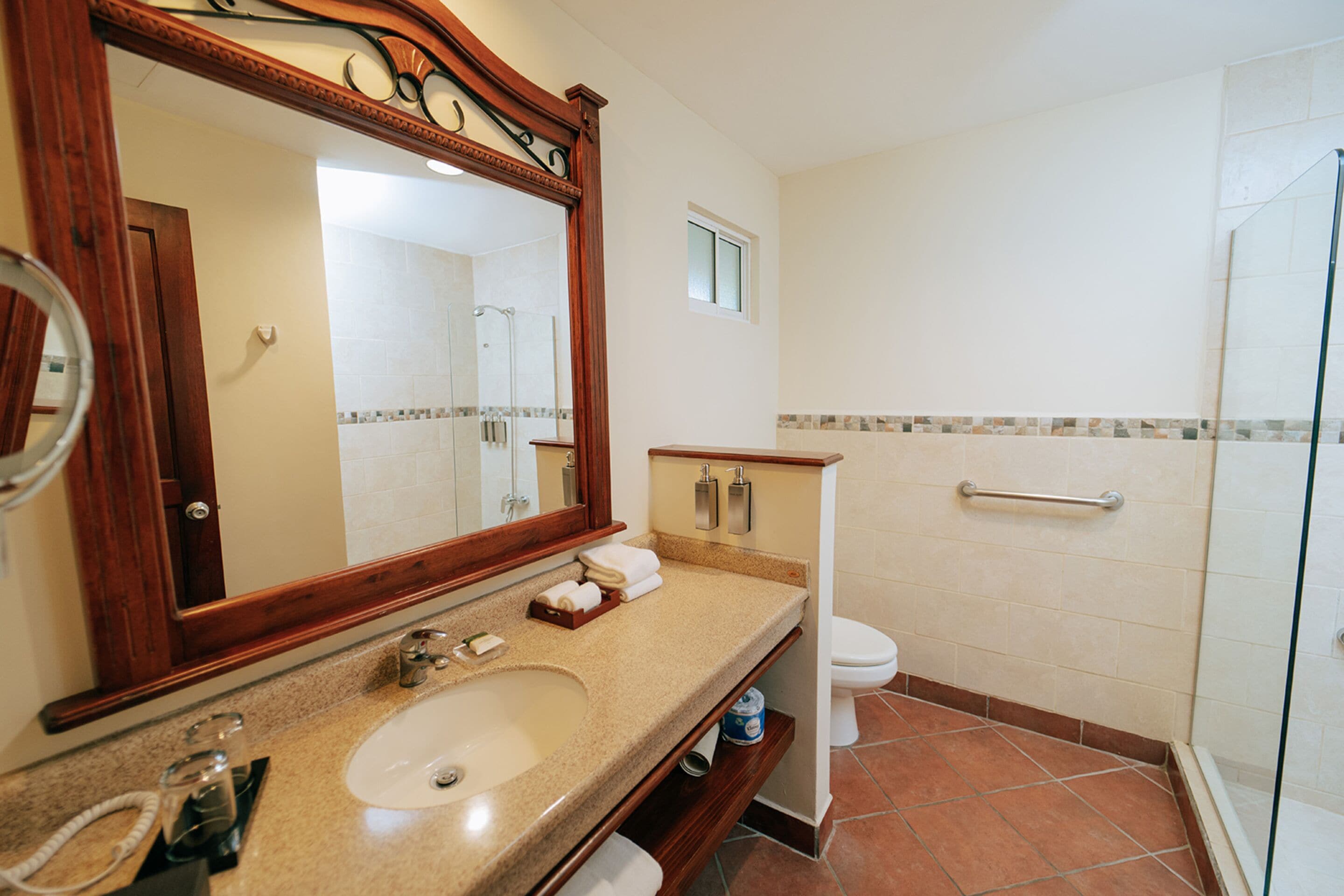 Une salle de bain équipée d’un lavabo, d’un miroir, de toilettes et d’une douche.
