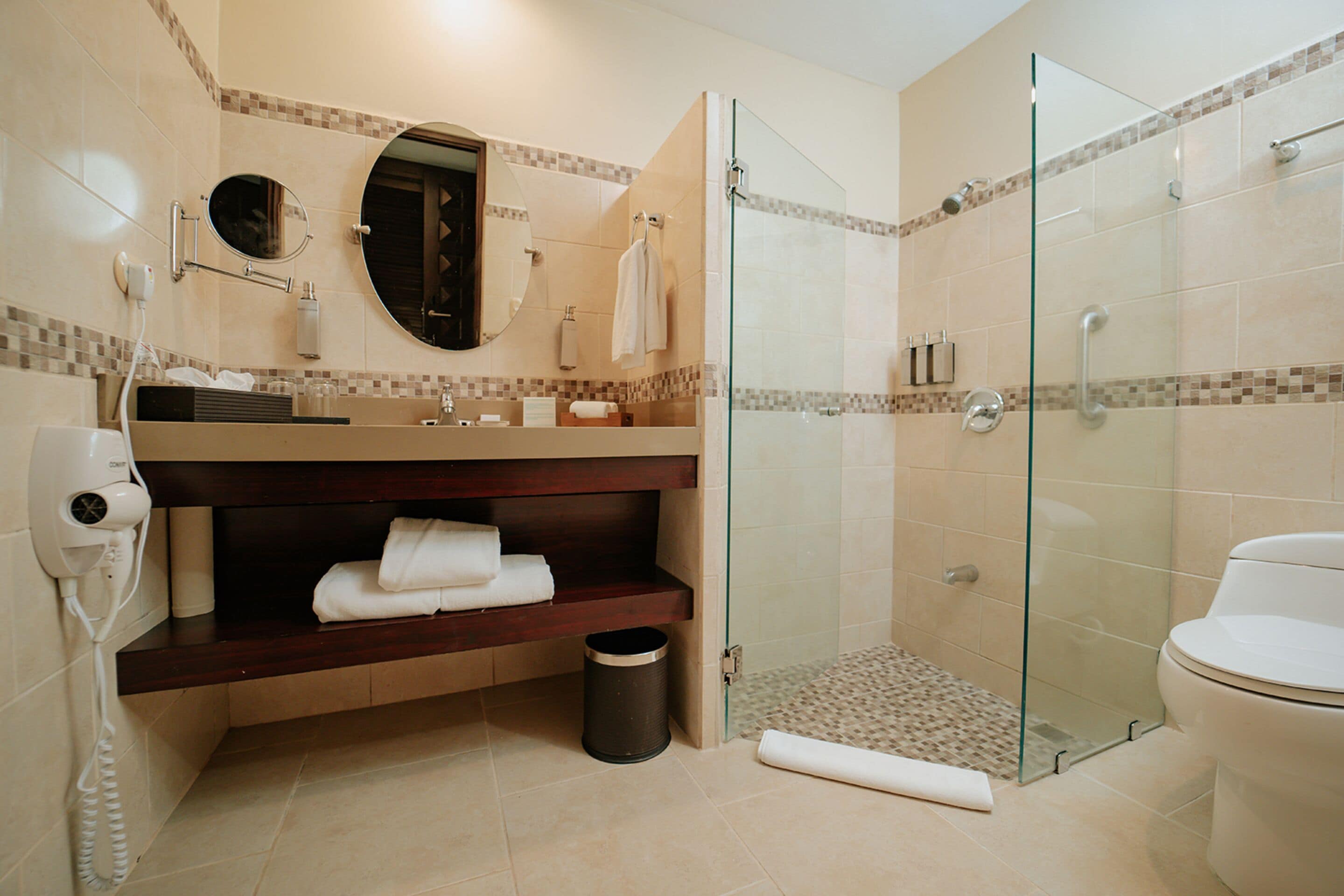 A modern bathroom with a glass-enclosed shower, a vanity with a mirror, and a toilet.