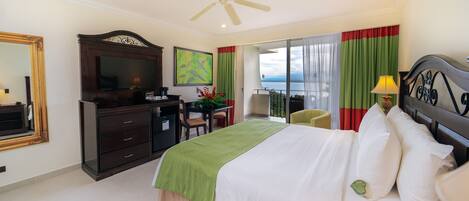 A hotel room with a bed, a desk, a chair, a television, and a balcony with a view.