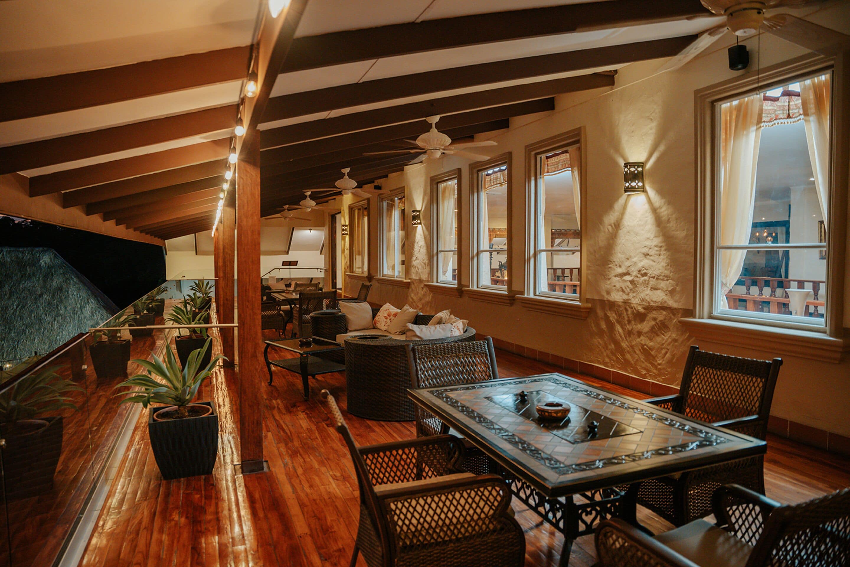A dining area with wooden flooring, wicker furniture, and a large table.
