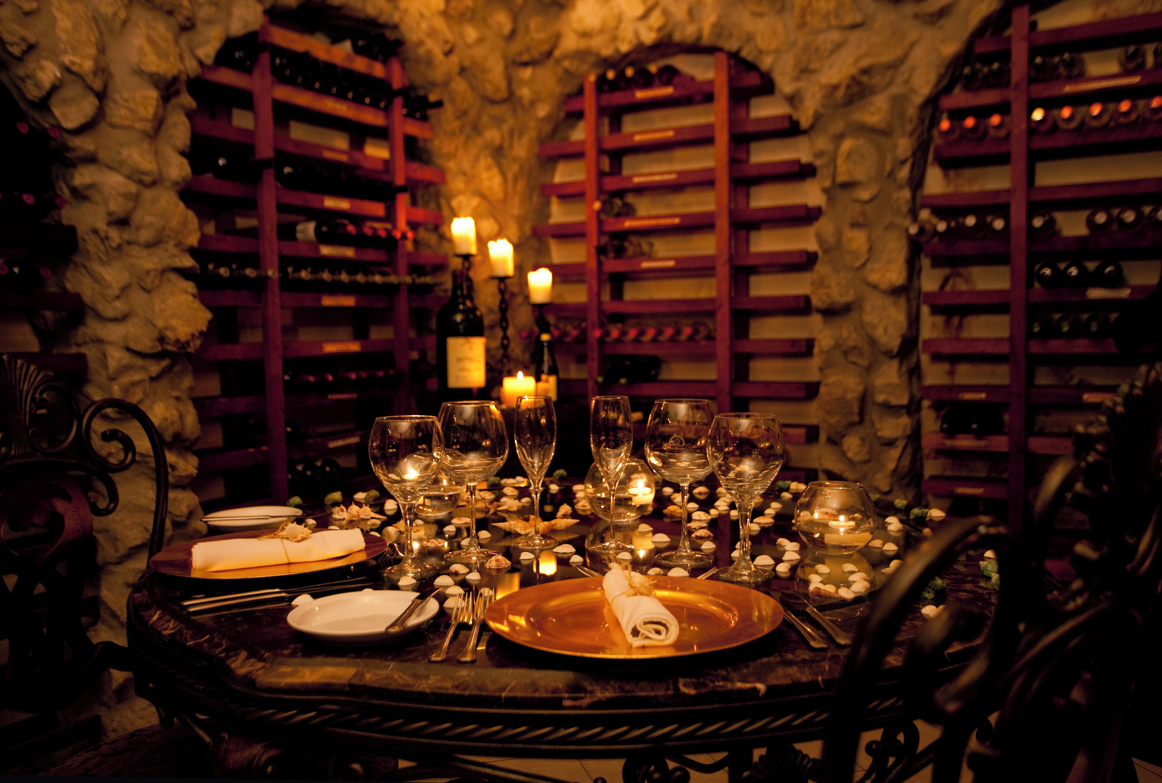 A table set for dining with wine bottles and glasses, candles, and a folded napkin.