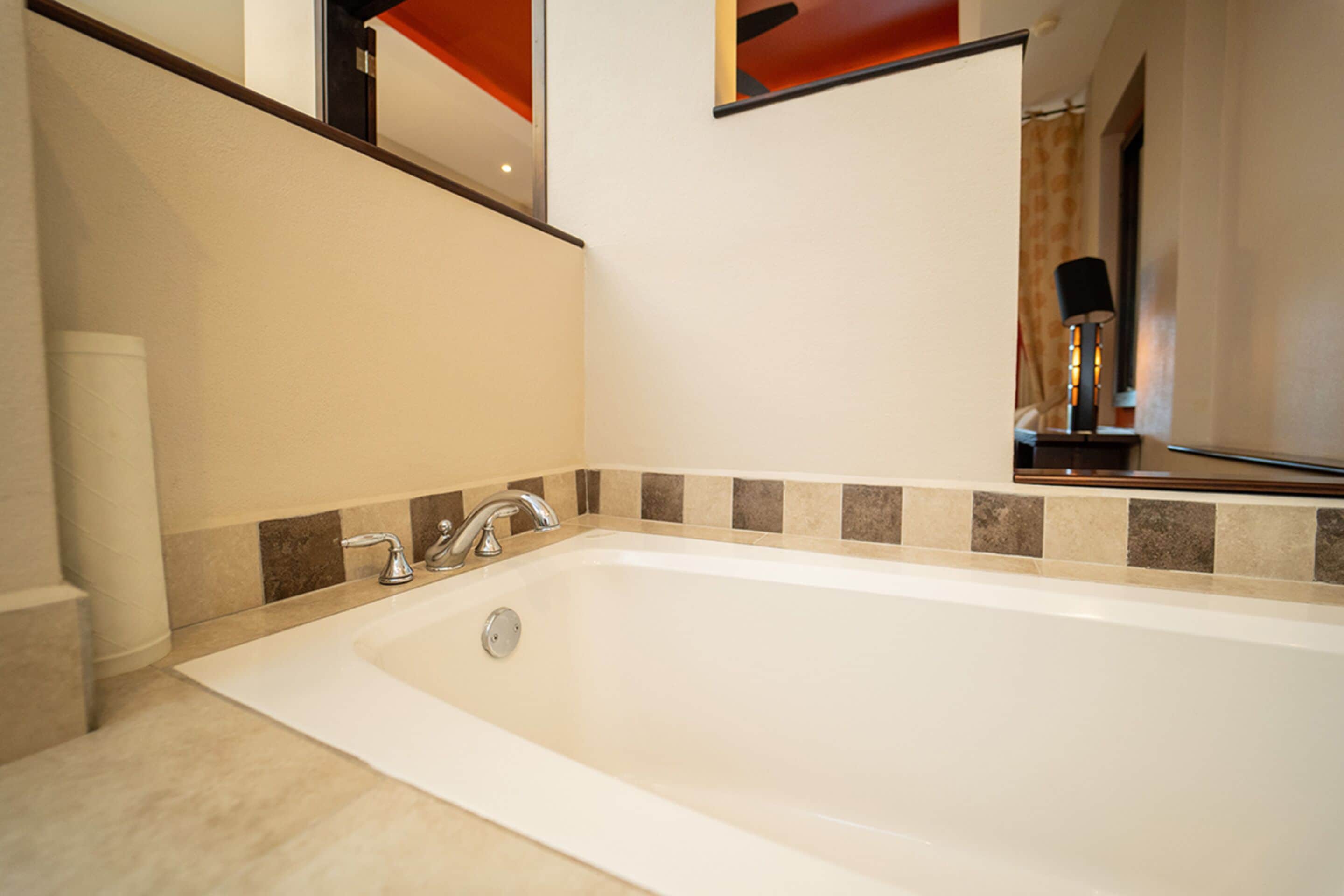 Ein modernes Badezimmer mit einer großzügigen Badewanne, einem Spiegel über dem Waschbecken und einem Handtuchspender.