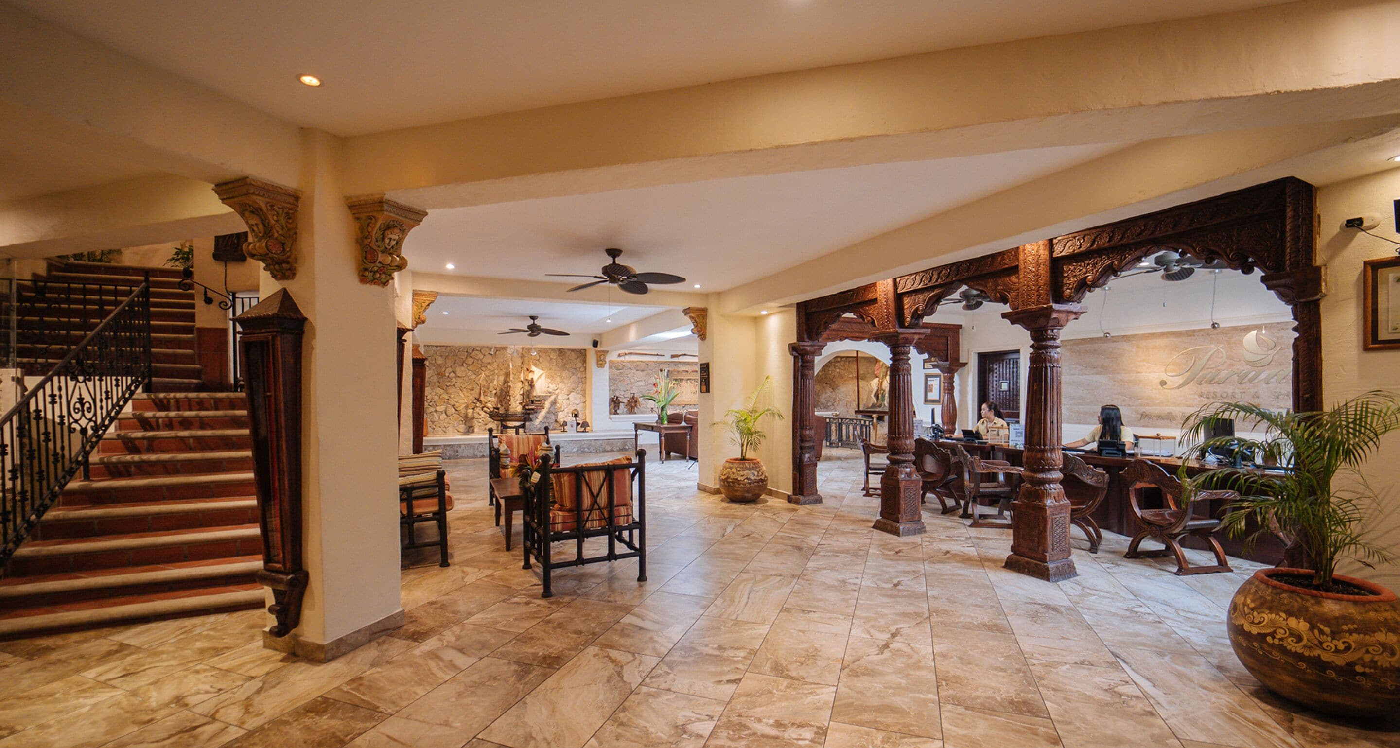 A spacious lobby with a marble floor, a staircase, and a dining area with wooden furniture.