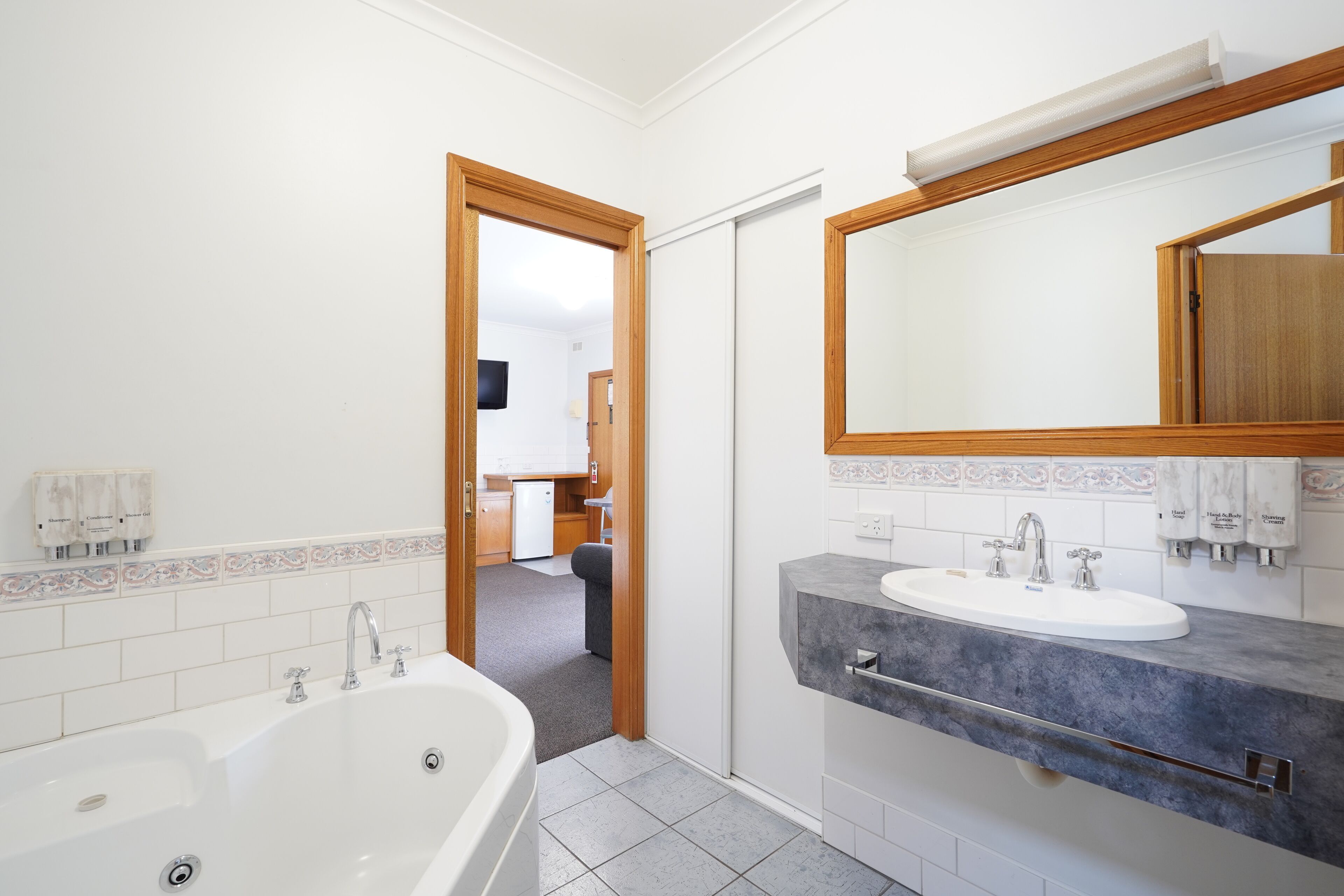 A modern bathroom with a double sink, a large mirror, and a walk-in shower.