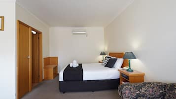 A hotel room with a bed, bedside tables, a lamp, and a patterned sofa.