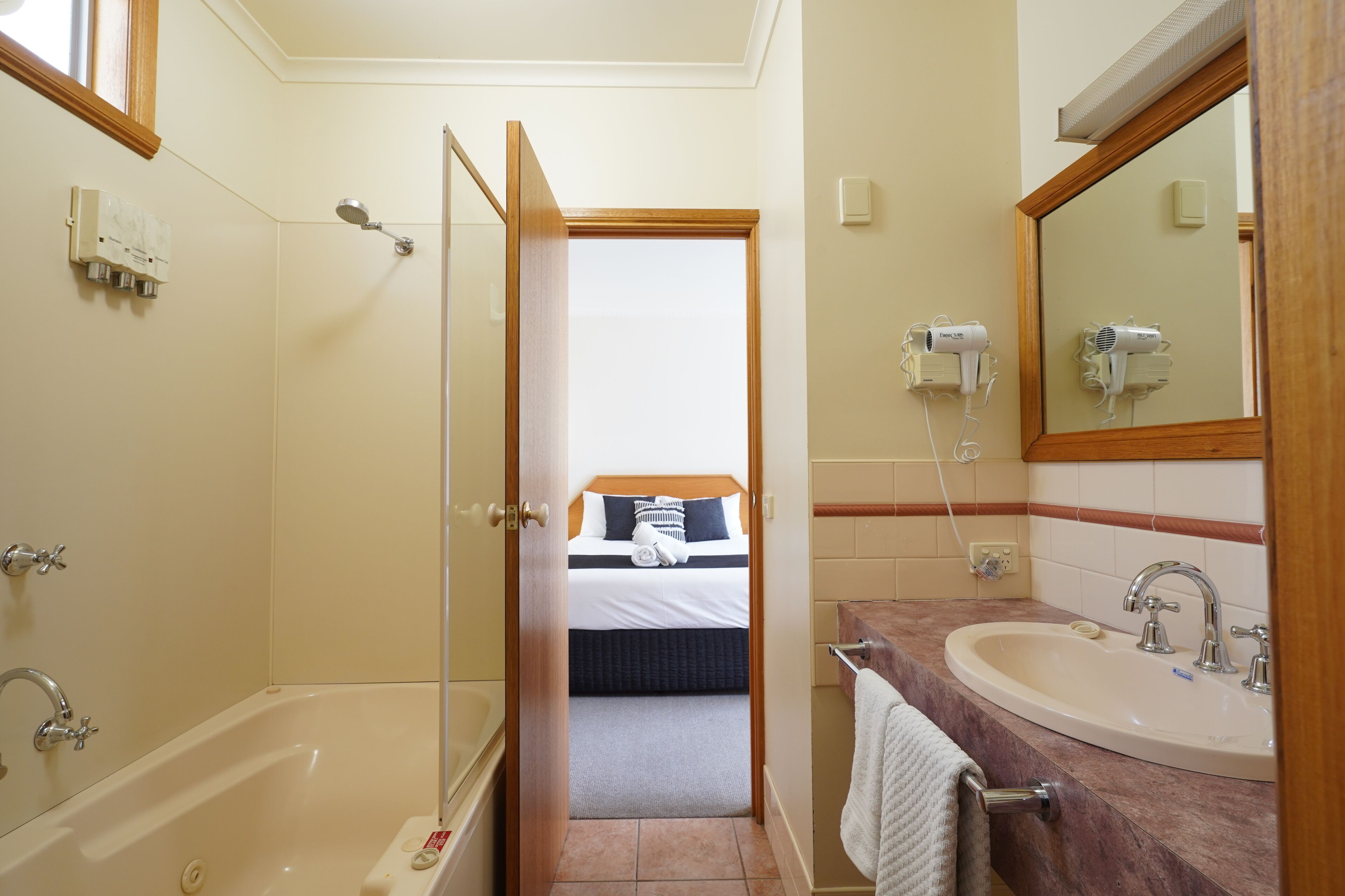 Un baño de hotel con bañera, lavabo y espejo.