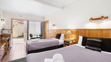 Habitación de hotel con dos camas, un escritorio, una silla y una mesita.