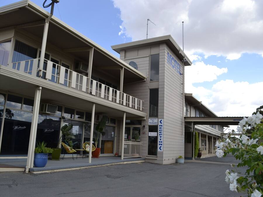 Un hotel con recepción, un balcón y un letrero que indica un restaurante.