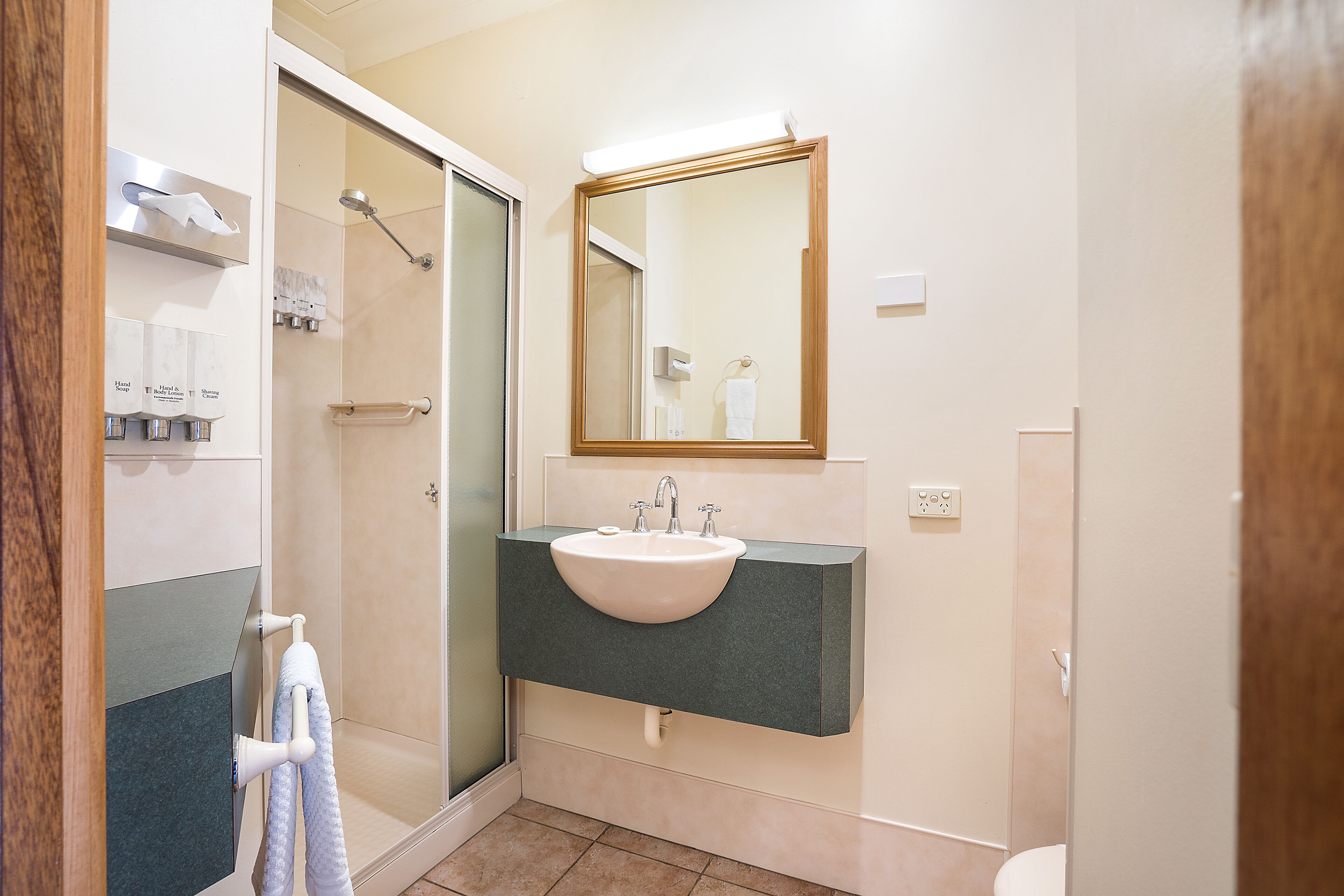 Un baño con lavabo, espejo, toallero y ducha.