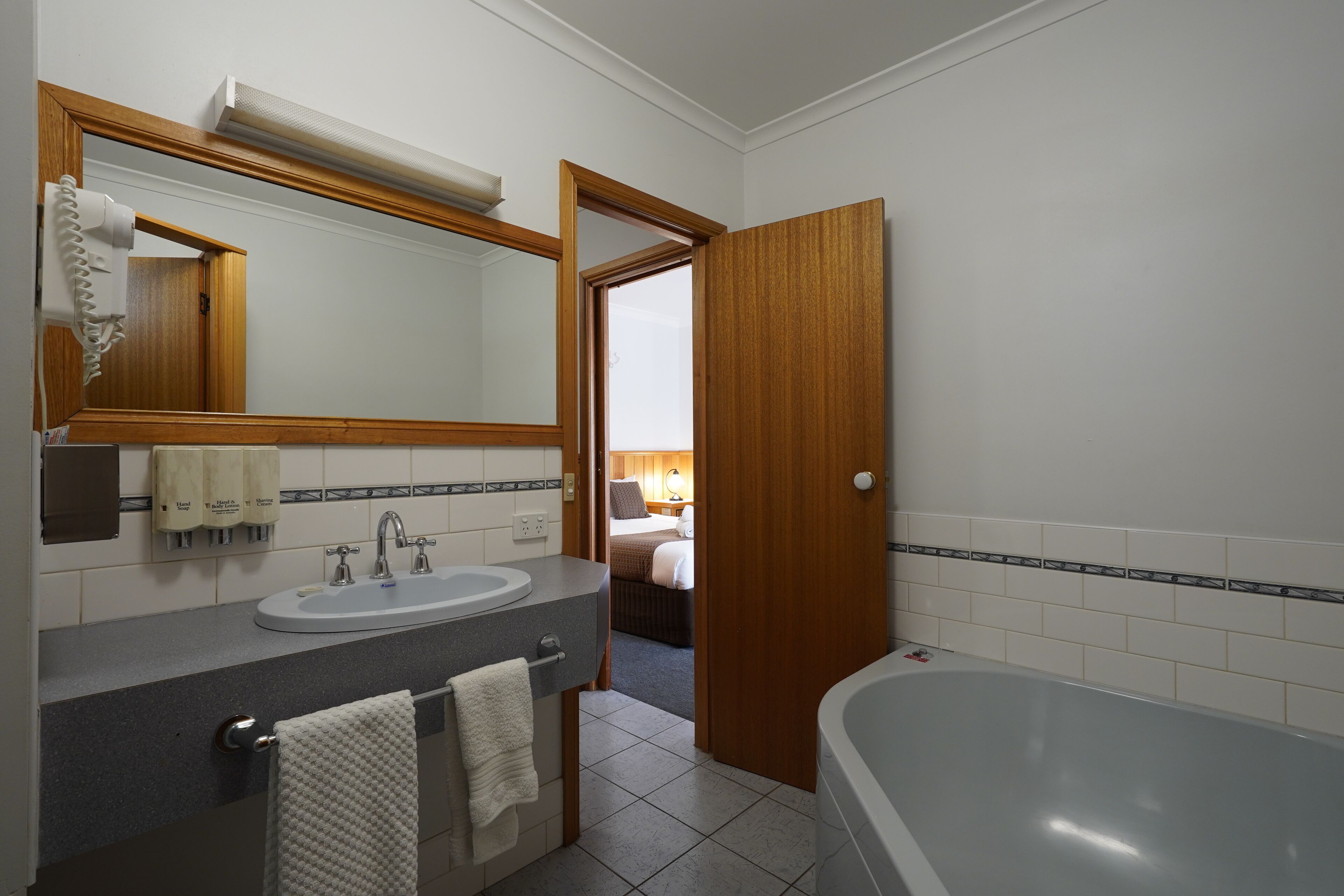A bathroom with a sink, mirror, towel rack, and a bathtub.