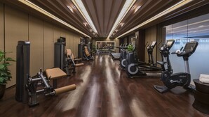 A gym with exercise equipment, wooden floors, and a view of the city. - Citadines Central Xi'an (Xi'an)
