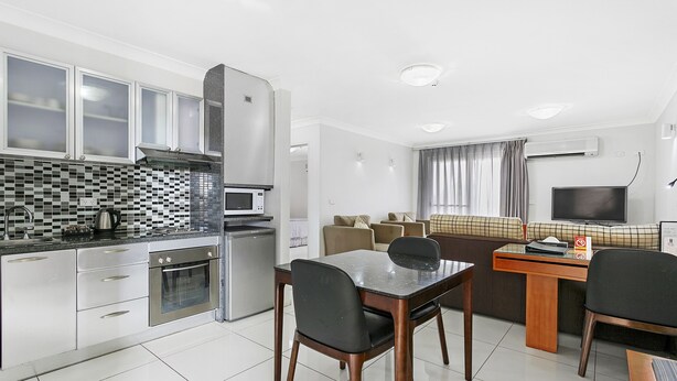 A modern kitchen with a dining area, a sofa, and a TV. - Comfort Inn & Suites Burwood (Burwood)