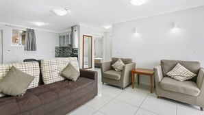 A modern living room with a brown sofa, beige armchairs, and a small wooden table. - Comfort Inn & Suites Burwood (Burwood)