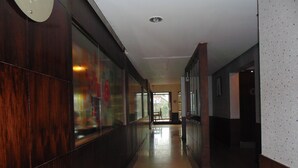 Um corredor comprido e estreito, com lambris de madeira em uma lateral e parede lisa na outra.