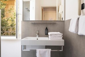 A modern bathroom with a white sink, a mirror, and a towel rack. - Ferrari Home (Rome)